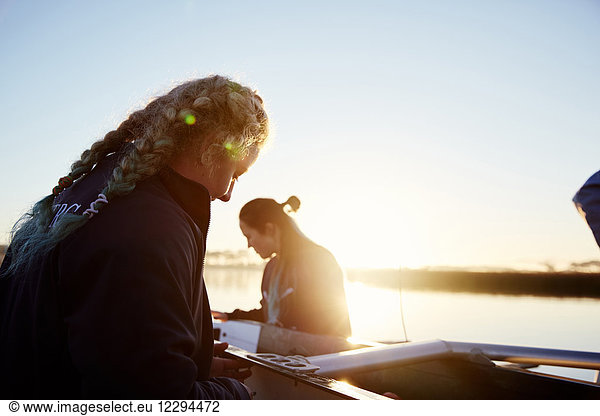 Female rowers preparing scull at sunrise lakeside