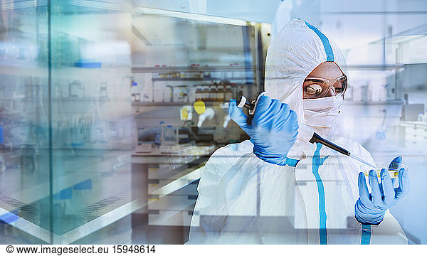 Female scientist in clean suit researching coronavirus in laboratory