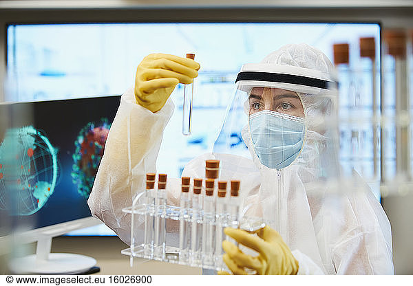 Female scientist in clean suit researching coronavirus vaccine