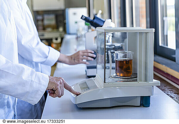 Female scientist weighing chemical on scale at laboratory