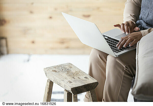 Female shop owner using laptop at wooden stool