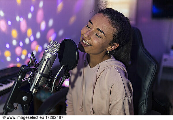 Female singer with eyes closed singing in studio