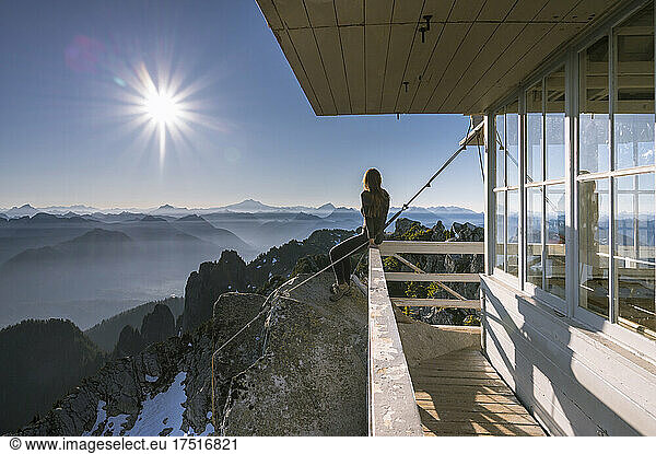 Female sitting on a fire lookout at sunrise in the cascades