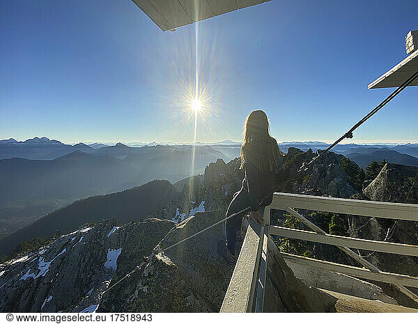 Female sitting on a fire lookout in the north cascade mountains