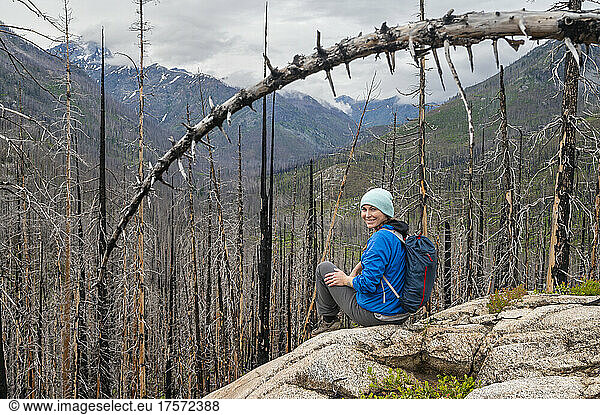 Female smiling sitting in a burned dead forest of trees