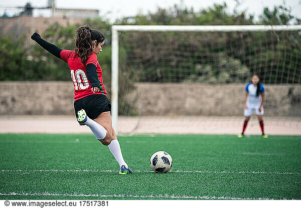female soccer player kicks the ball towards the goal in a stadium