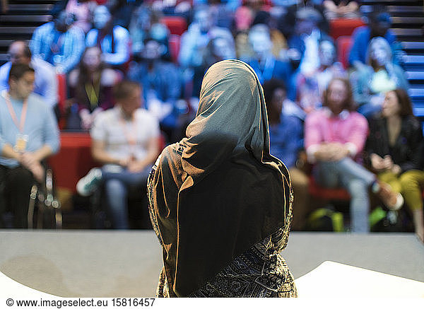 Female speaker in hijab on stage talking to audience