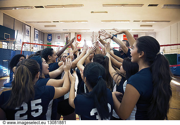 Female sports team cheering at indoor volleyball court