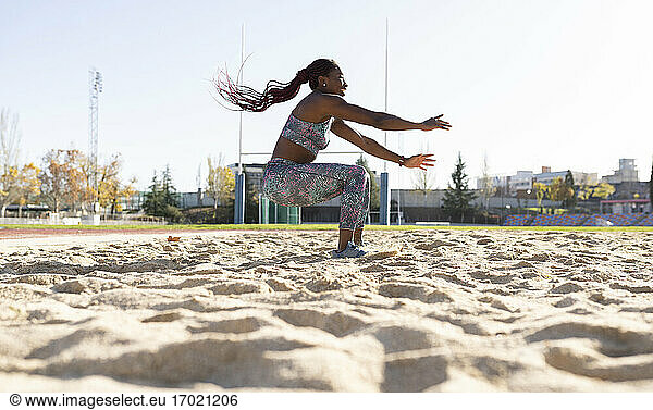 Female sportsperson balancing on sand against clear sky during sunny day