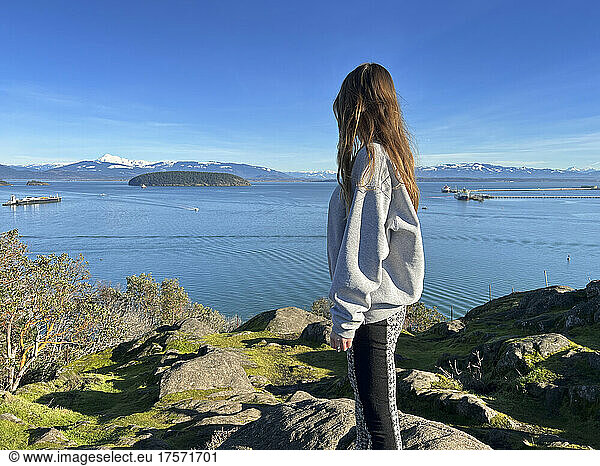 Female standing on cliff looking at water views
