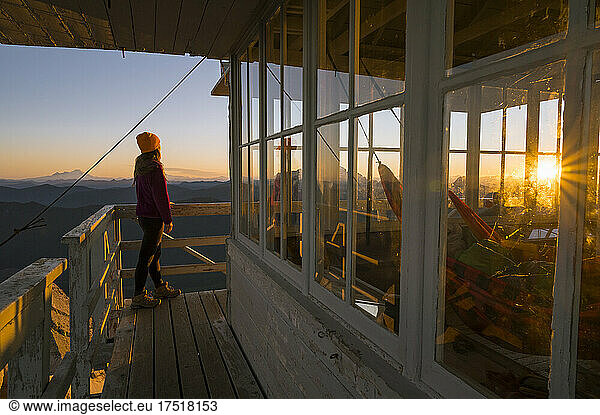 Female standing on mount pilchuck fire lookout at sunrise