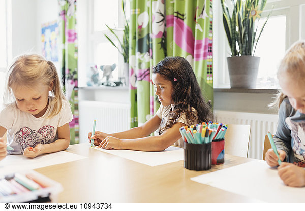 Female students drawing at table in classroom