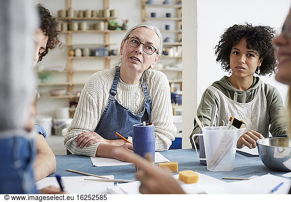 Female students listening sitting at table in art class