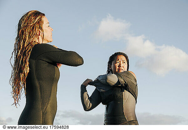 Female surfers removing wetsuit after surfing