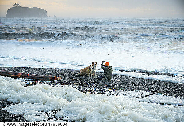 Female taking photo of their dogs on the olympic coast