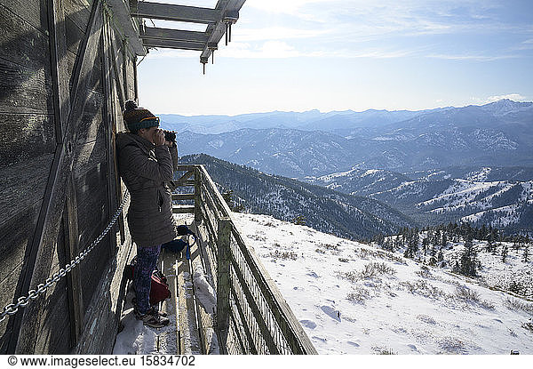 Female Taking Photograph From A Fire Lookout In The Mountains