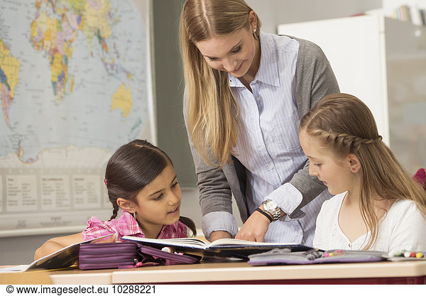 Female teacher helping students in classroom  Munich  Bavaria  Germany