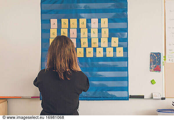 Female teacher organizing letters on her board in her classroom.