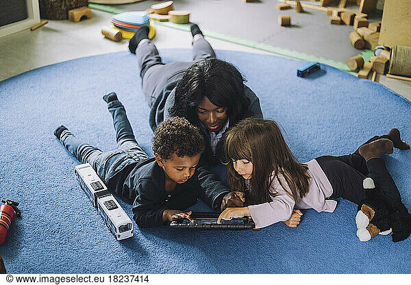 Female teacher using digital tablet with students in day care center