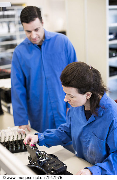 Female technician analyzing machine while colleague looking at her in industry