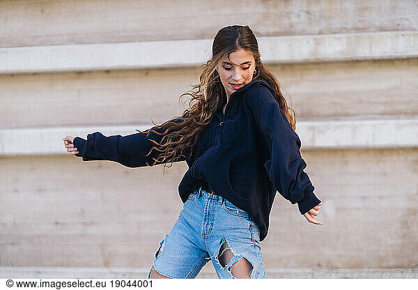 Female Teenager Dancing Next To A Concrete Wall.