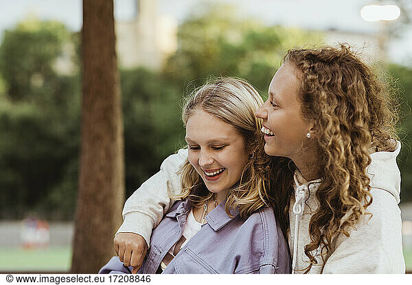 Female teenager friends laughing in park