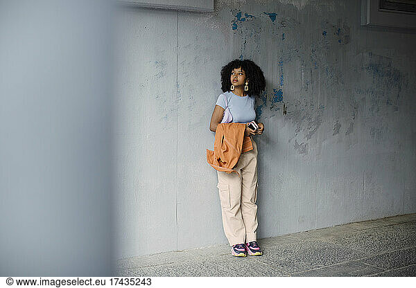 Female teenager standing against wall