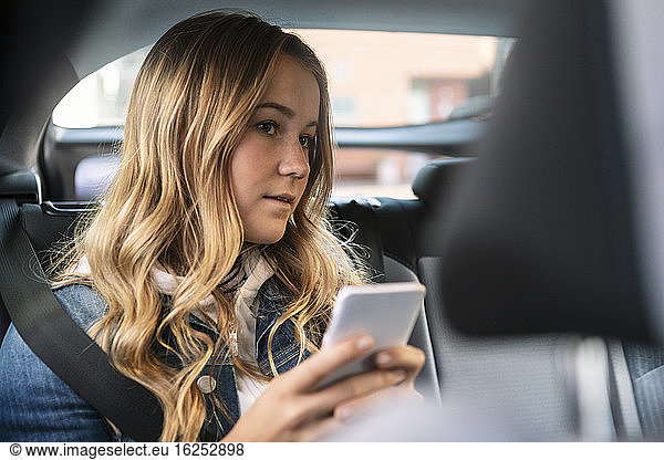 Female teenager using phone while sitting in car