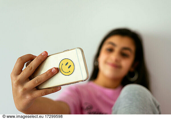 Female teenager using smartphone on bed and taking photos
