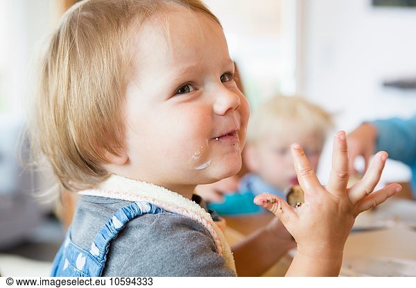 Female toddler with sticky hands at tea table
