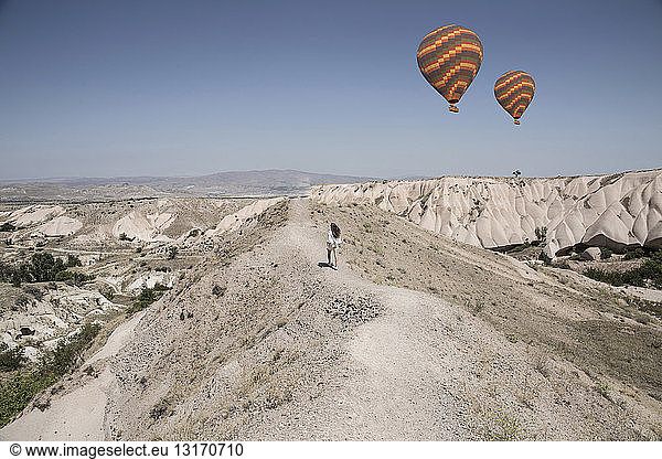 Female tourist and hot air balloons in rock formation landscape  Cappadocia  Anatolia Turkey