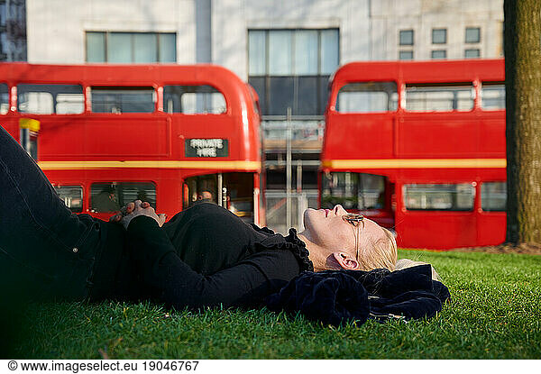 Female tourist lying down on meadow of London