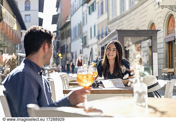 Female tourist talking to man at sidewalk cafe
