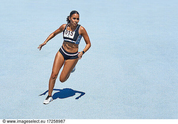 Female track and field athlete on sunny blue track