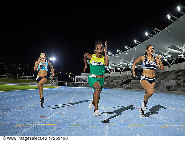 Female track and field athlete running in competition on track