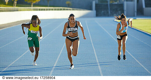 Female track and field athletes competing on sunny track