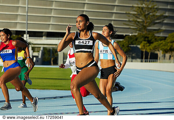 Female track and field athletes running in competition on race track