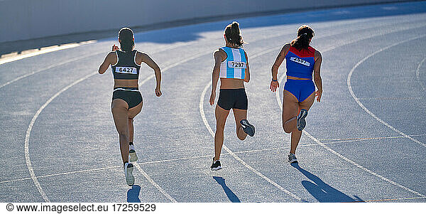 Female track and field athletes running in competition on track