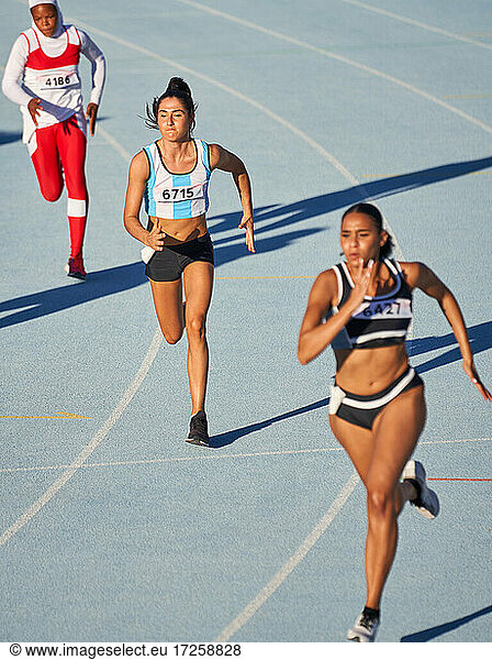 Female track and field athletes running on track in competition