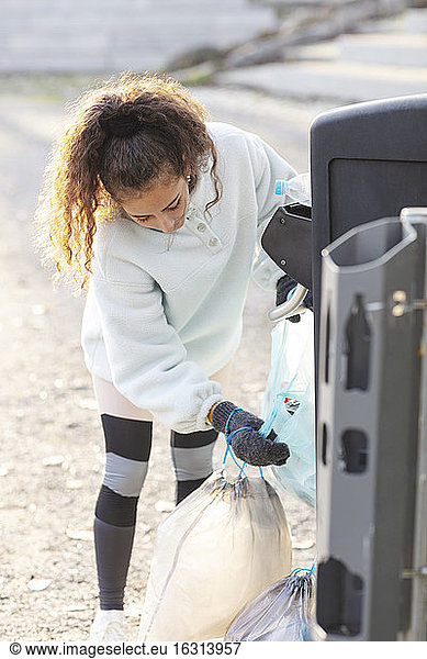 Female volunteer throwing plastic waste in garbage can