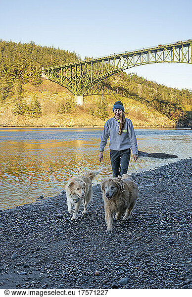 Female walking on a beach with their dogs at Deception Pass