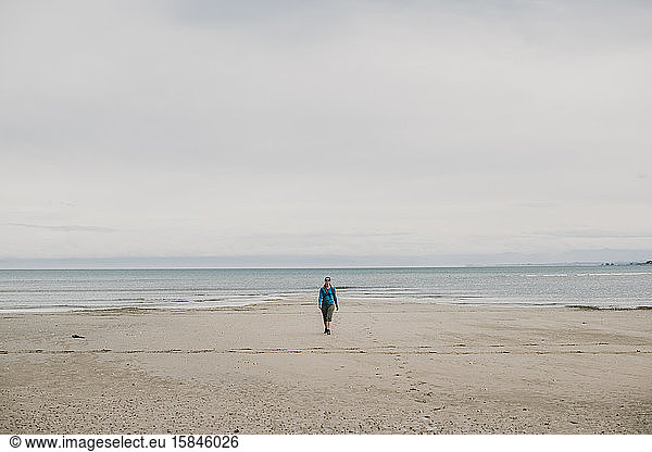 female walks alone on beach Abel Tasman National Park New Zealand