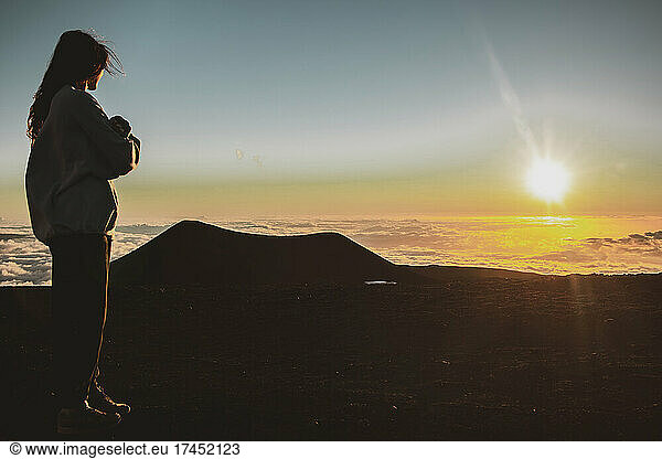 female watches sunset on top of Mauna Kea