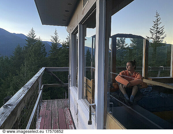 Female watching sunset inside a fire lookout in the mountains