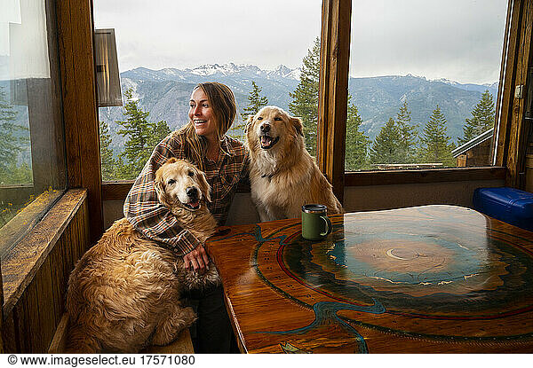 Female with dogs having coffee in a mountain cabin