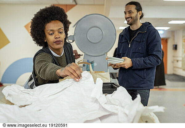Female worker reaching at papers while working at recycling center