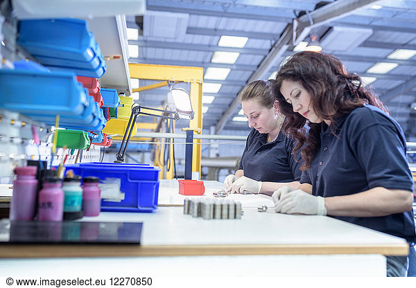 Female workers painting wax masking onto components in electroplating factory
