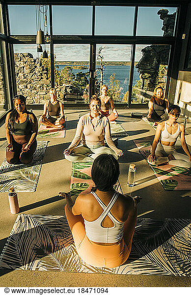 Female yoga coach instructing students during class at retreat center