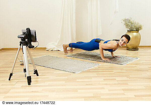 female yoga trainer training online via smartphone on a tripod
