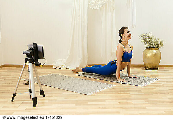 female yoga trainer training online via smartphone on a tripod